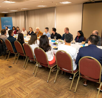 Foto com colaboradores e sócios em uma grande mesa, dialogando entre si.